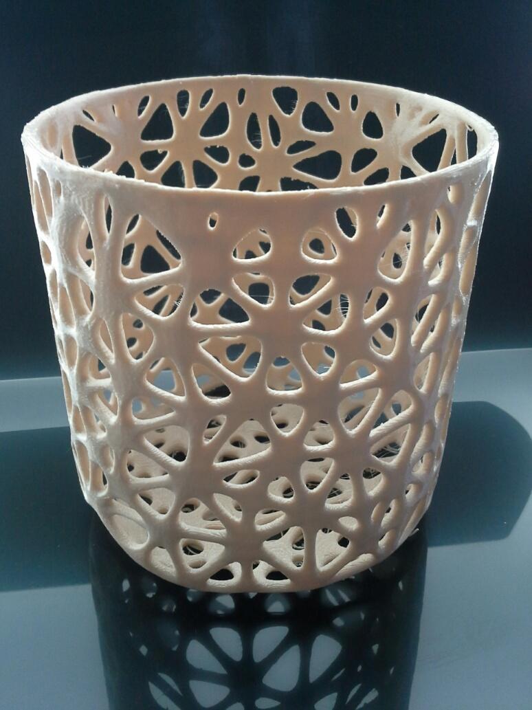 Ivory openwork 3D-printed toothbrush holder on a dark tabletop; third-party illustrative reference.